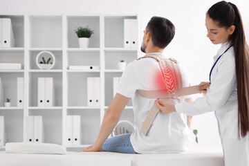 Young man with back brace and female physiotherapist in rehabilitation center