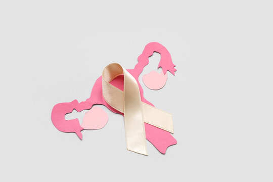 Paper uterus with beige ribbon on light background. Cancer awareness concept