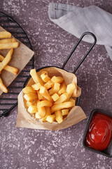 Deep fryer basket with french fries and ketchup on grey background