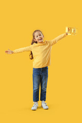 Cute little girl with toy plane on yellow background