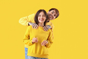 Young couple smiling on yellow background
