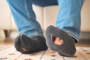 men feet with dirty socks while sitting on sofa 