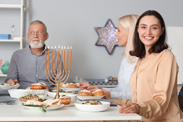 Young woman having dinner with her parents at home on Hanukkah