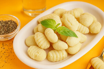 Plate with tasty gnocchi and spices on orange background, closeup