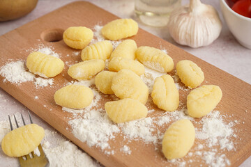 Wooden board with tasty gnocchi and fork on light background, closeup