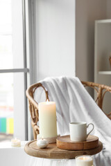 Burning candles with coffee cup on bathtub in room, closeup