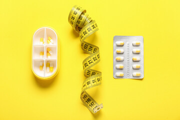 Container, blister pack with weight loss pills and measuring tape on yellow background