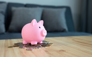 A pink piggy bank with various coins on table.