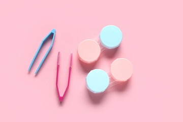 Containers for contact lenses with tweezers on pink background