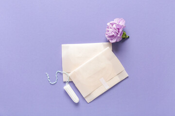 Menstrual pads with tampon and carnation flower on purple background