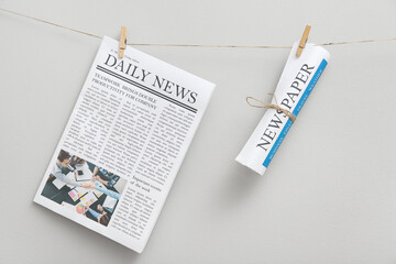 Newspapers hanging on rope against white background