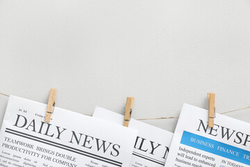 Newspapers hanging on rope against white background
