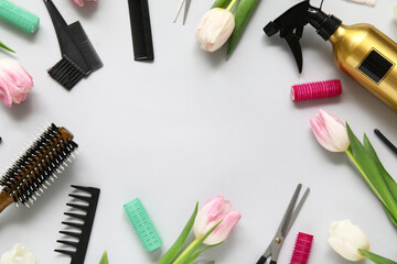 Frame made of hairdresser's tools with beautiful tulips on grey background