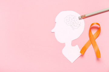 Paper human head and orange ribbon on pink background.  Multiple Sclerosis Awareness Month