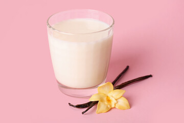 Glass of milk, vanilla sticks and flower on pink background