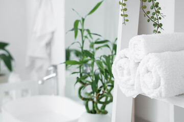 Clean towels on shelf in light bathroom, closeup