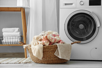 Wicker basket with dirty clothes near washing machine in laundry room