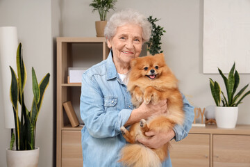 Senior woman holding Pomeranian dog at home