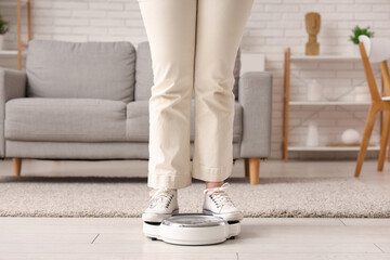 Young woman measuring weight on scales at home, closeup. Weight gain concept - Powered by Adobe