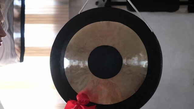 A small hammer and a gong in close-up. Women's hands beat the gong with a small soft hammer. A gong for meditation . 4K Video
