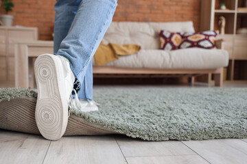 Young woman tripping on carpet at home, closeup