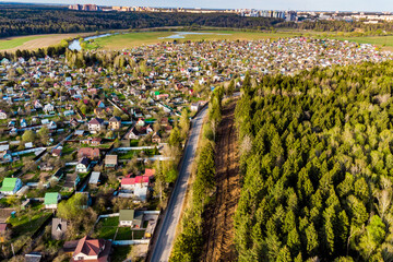 Aerial view of dense dacha development and forest separated by a road