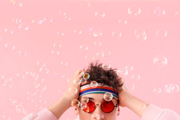 Cool young man with soap bubbles on pink background, closeup