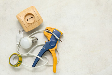 Wire stripper, light bulb, cable and electric socket on white grunge background