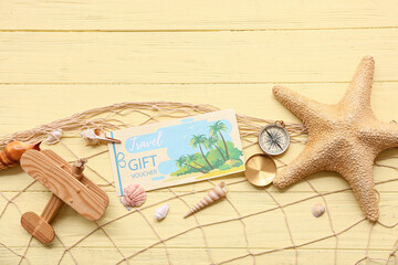 Composition with travel gift voucher, vintage compass, fish net and starfish on color wooden...