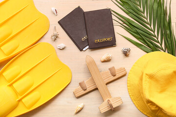 Composition with passports, toy plane and beach accessories on wooden background