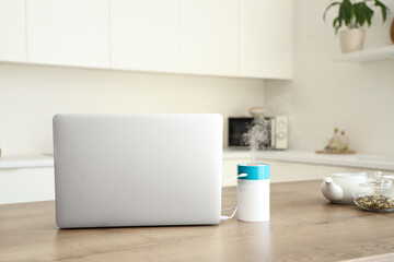 Air humidifier with laptop on table in kitchen