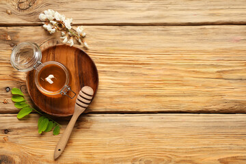 Jar of sweet honey with acacia flowers and dipper on wooden background