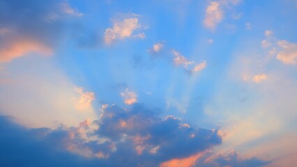 A vibrant sunset sky with dramatic rays of light piercing through scattered clouds. The clouds are...
