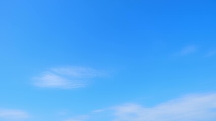 Obraz premium A clear, bright blue sky with a few wispy white clouds scattered across it. The sky is a vibrant shade of blue, creating a serene and peaceful atmosphere. Nature's beauty background. 