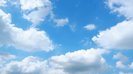A bright blue sky filled with large, fluffy white clouds. The clouds are billowy and soft, creating a picturesque scene against the vibrant blue background. Nature's beauty background.
