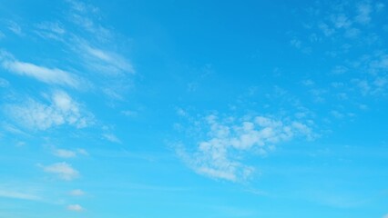 A vibrant blue sky adorned with a few scattered, wispy white clouds. The clear sky and delicate...