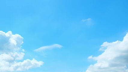 A bright blue sky with a few fluffy white clouds. The clouds are primarily gathered at the edges,...