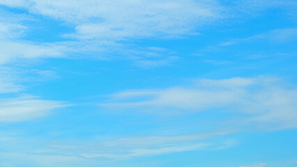 A bright blue sky with a few scattered, thin white clouds. The sky's vibrant color and the delicate...