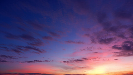 A beautiful sunrise with a sky transitioning from deep purple and blue hues at the top to vibrant pinks and oranges near the horizon. Wispy clouds add texture to the scene. Sunrise sky background.
