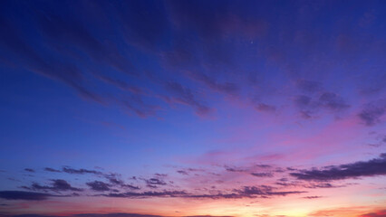 Fototapeta premium A stunning sunrise with a sky painted in deep shades of blue and purple, transitioning to lighter pinks and oranges near the horizon. Wispy clouds add texture and contrast. Sunrise sky background. 