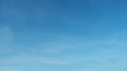 A clear blue sky with a few thin, wispy clouds spread across the frame. The sky transitions from a deeper blue at the top to a lighter blue towards the bottom, giving a serene and peaceful feel.
