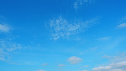 A vivid blue sky with a scattering of thin, white clouds. The clouds are dispersed evenly, creating...