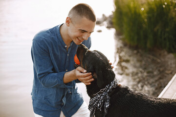 Man with rotweiller dog playing together near the lake