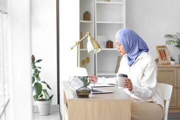 Muslim businesswoman with coffee cup working at home office