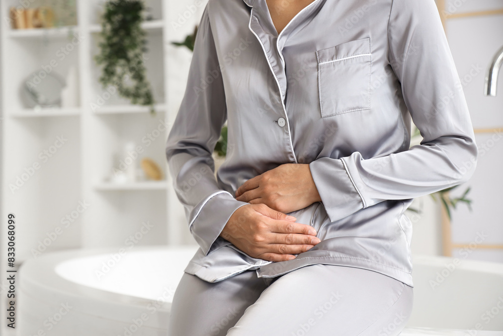 Sticker young woman suffering from menstrual cramps in bathroom, closeup