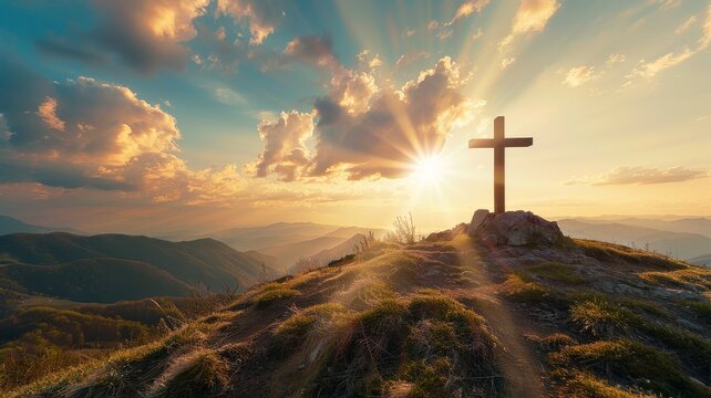 a cross on a mountain top with sun flare backlighting it.