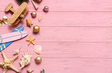 Wooden airplane, toy surfboard, starfish and Christmas decor on pink wooden background. Top view