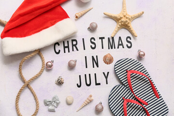 Santa's hat, flip-flops and text CHRISTMAS IN JULY on white background. Top view