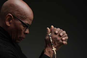 praying to god with hands together on dark background stock photo	