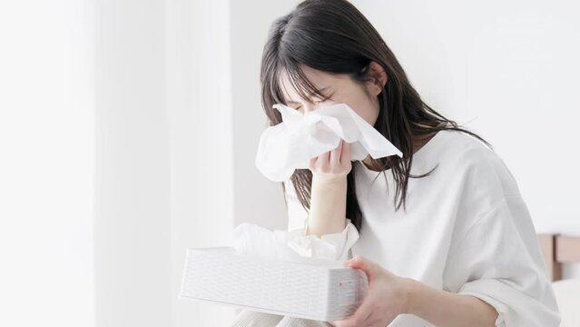 部屋で鼻をかむ女性